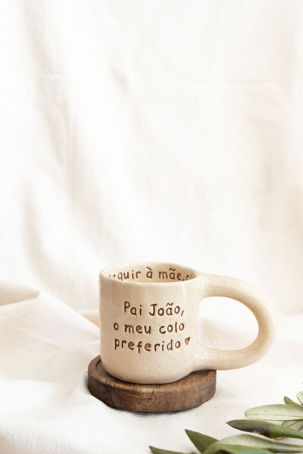 Caneca de cerâmica bege com texto e base de madeira