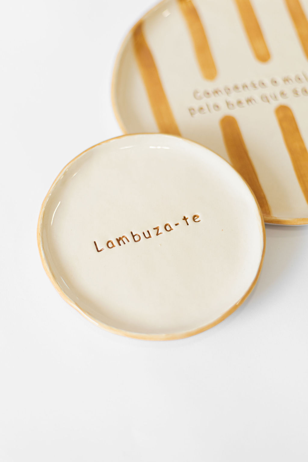 Dois pratos de cerâmica com acabamento creme e detalhes em bege e texto em relevo