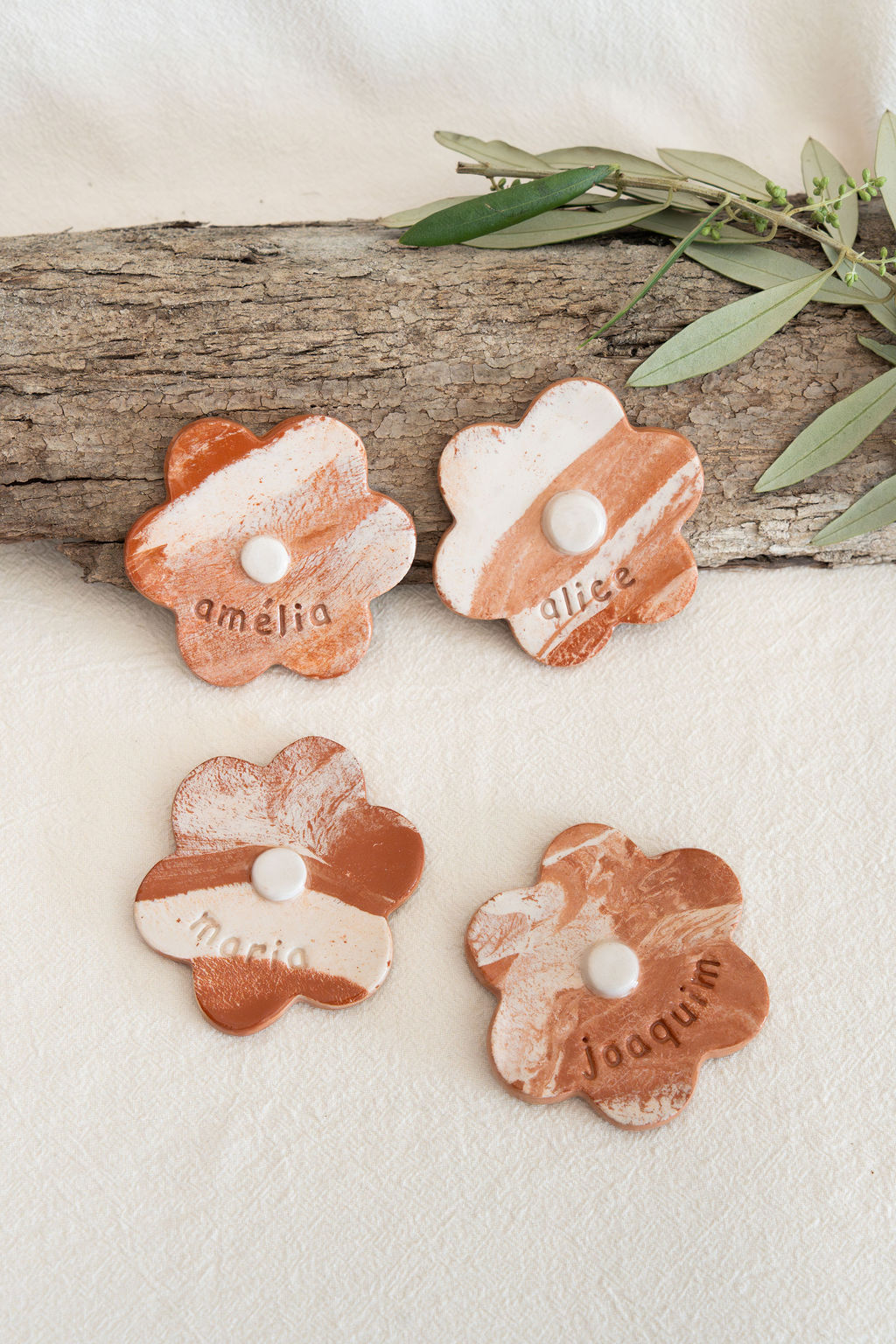 Peças decorativas de cerâmica em forma de flor com nomes gravados e padrão marmoreado