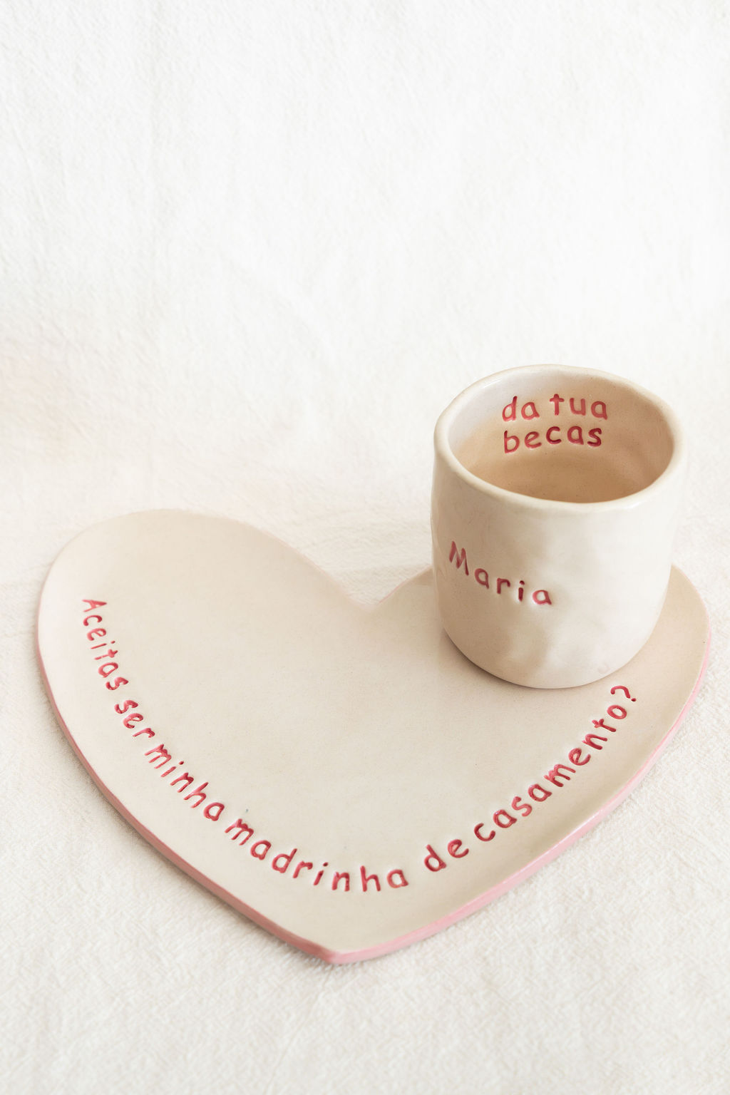 Conjunto cerâmica com prato em forma de coração e copo, texto vermelho em português.