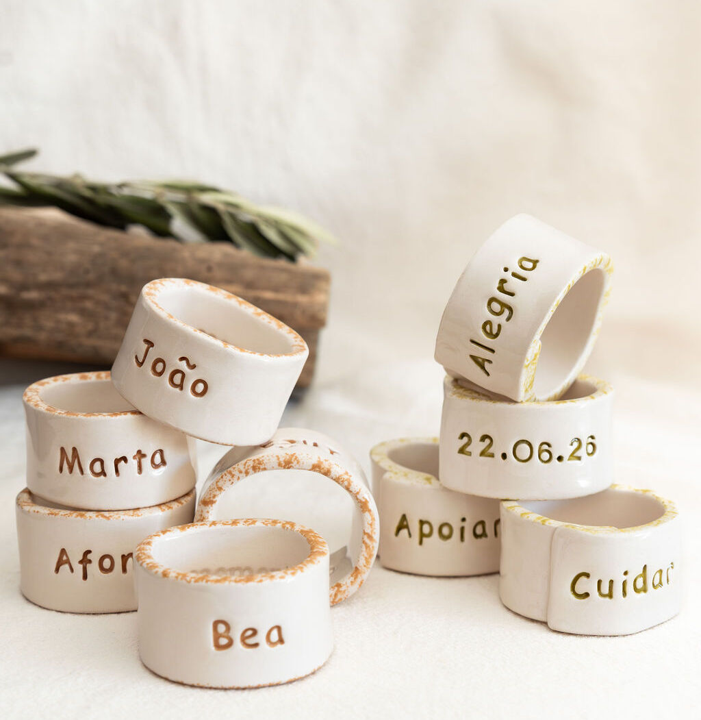 Argolas de guardanapo em cerâmica branca com textos variados e bordas castanhas e verdes