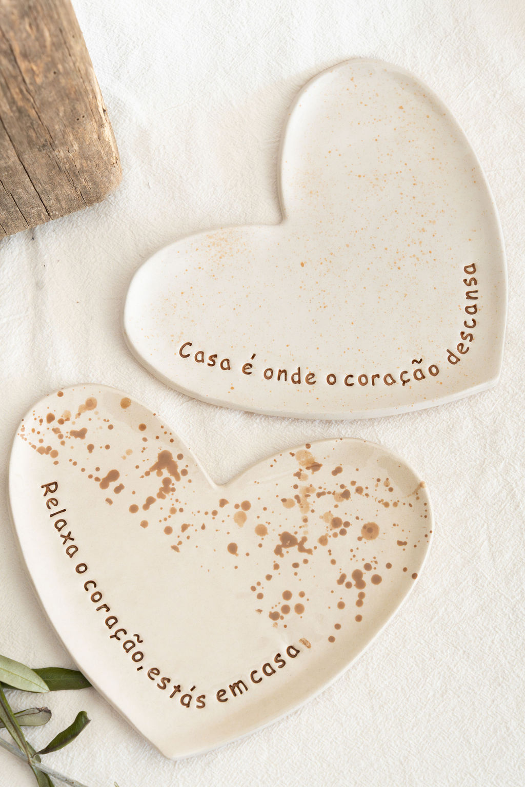 Dois pratos de cerâmica em formato de coração com texto em português colocados sobre tecido branco