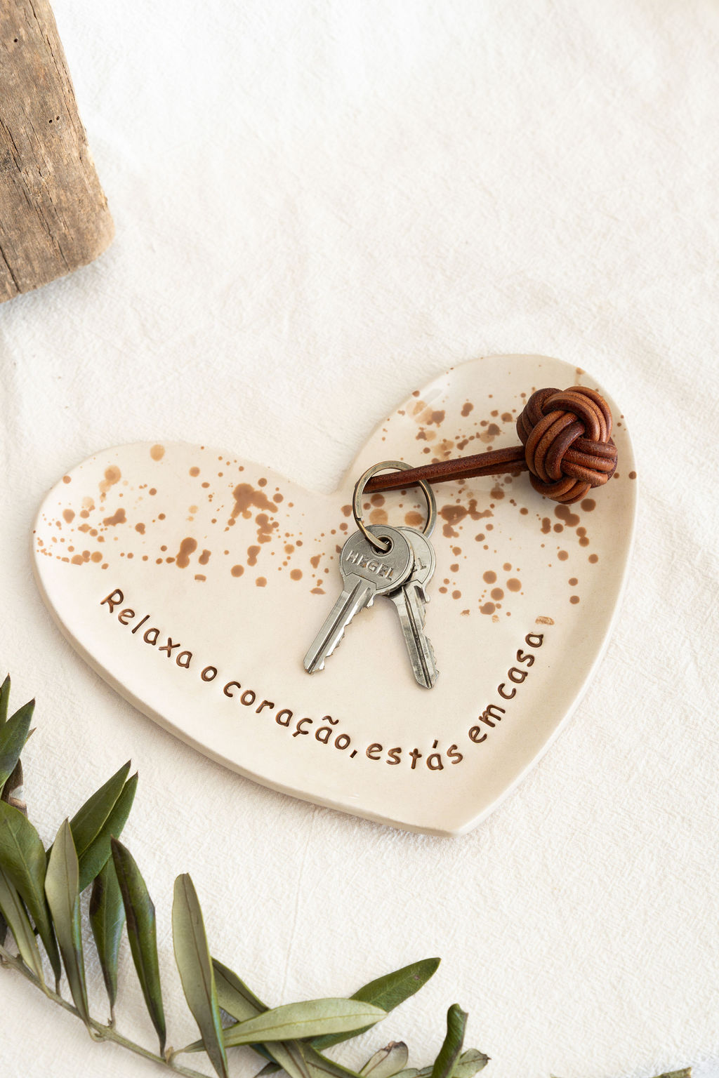 Prato de cerâmica em forma de coração com manchas castanhas e texto gravado