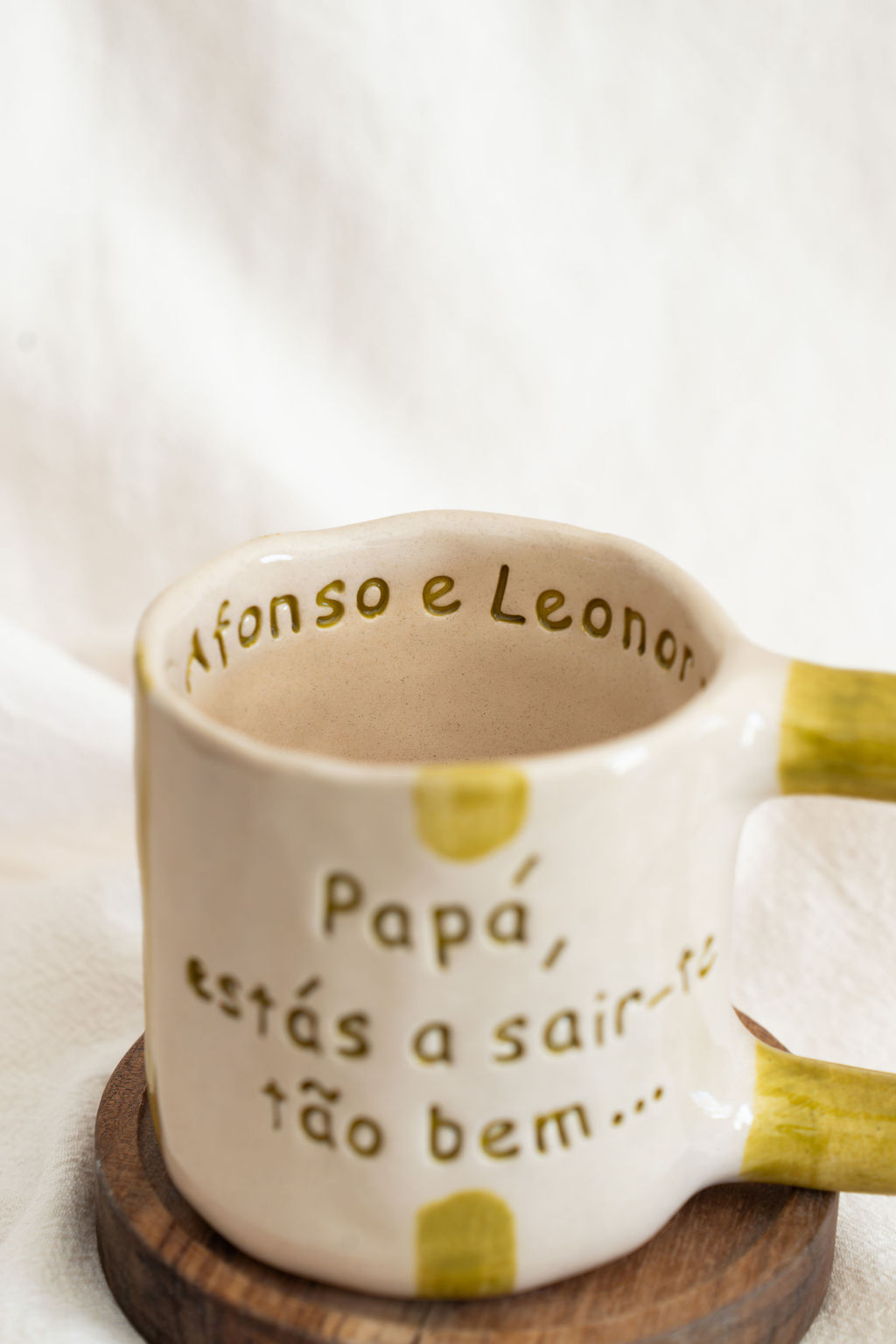 Caneca de cerâmica branca com texto gravado em verde e riscas amarelas