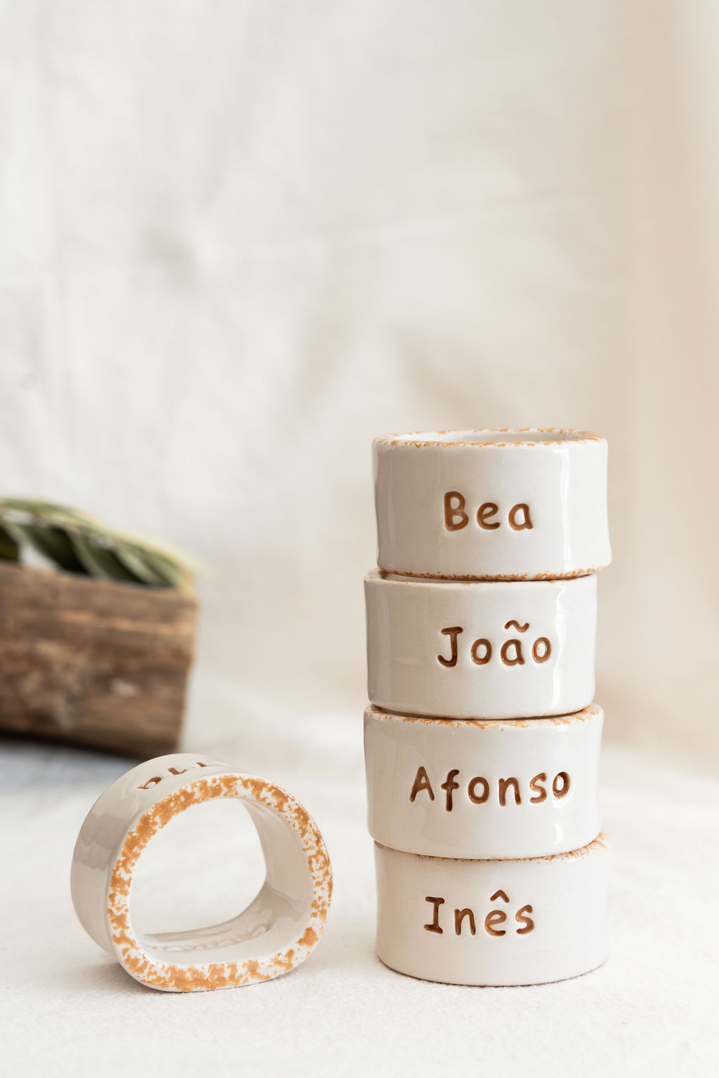 Argolas de guardanapo em cerâmica branca com nomes gravados e bordas castanhas