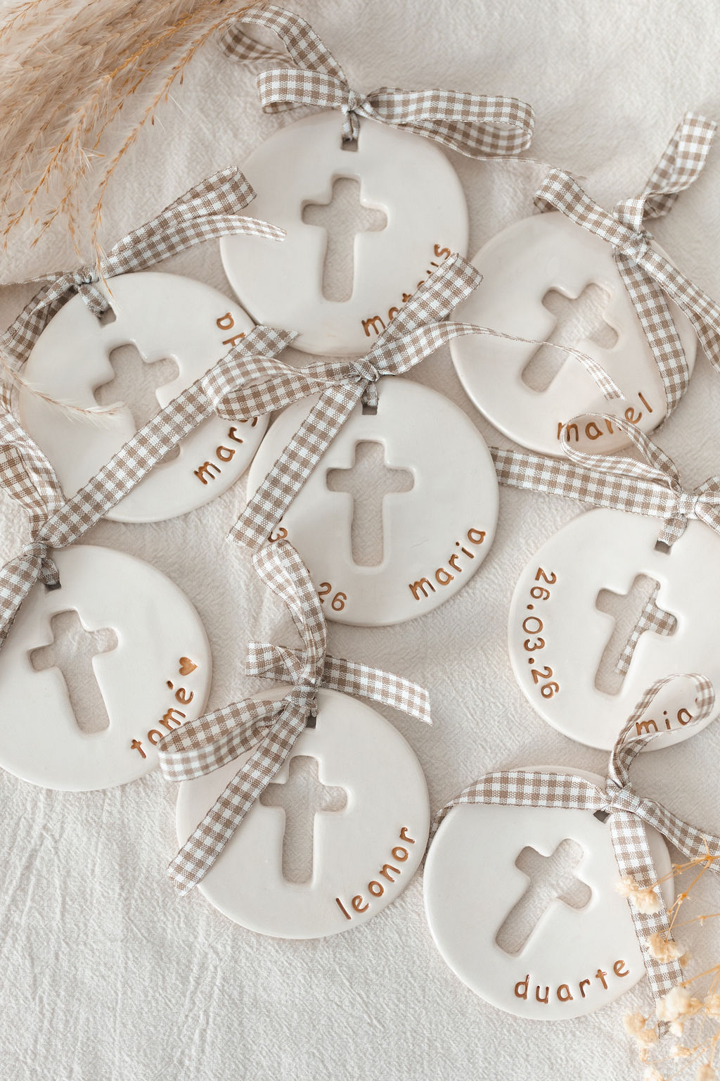 Pendentes redondos em cerâmica branca com cruz recortada e fitas às quadrículas.