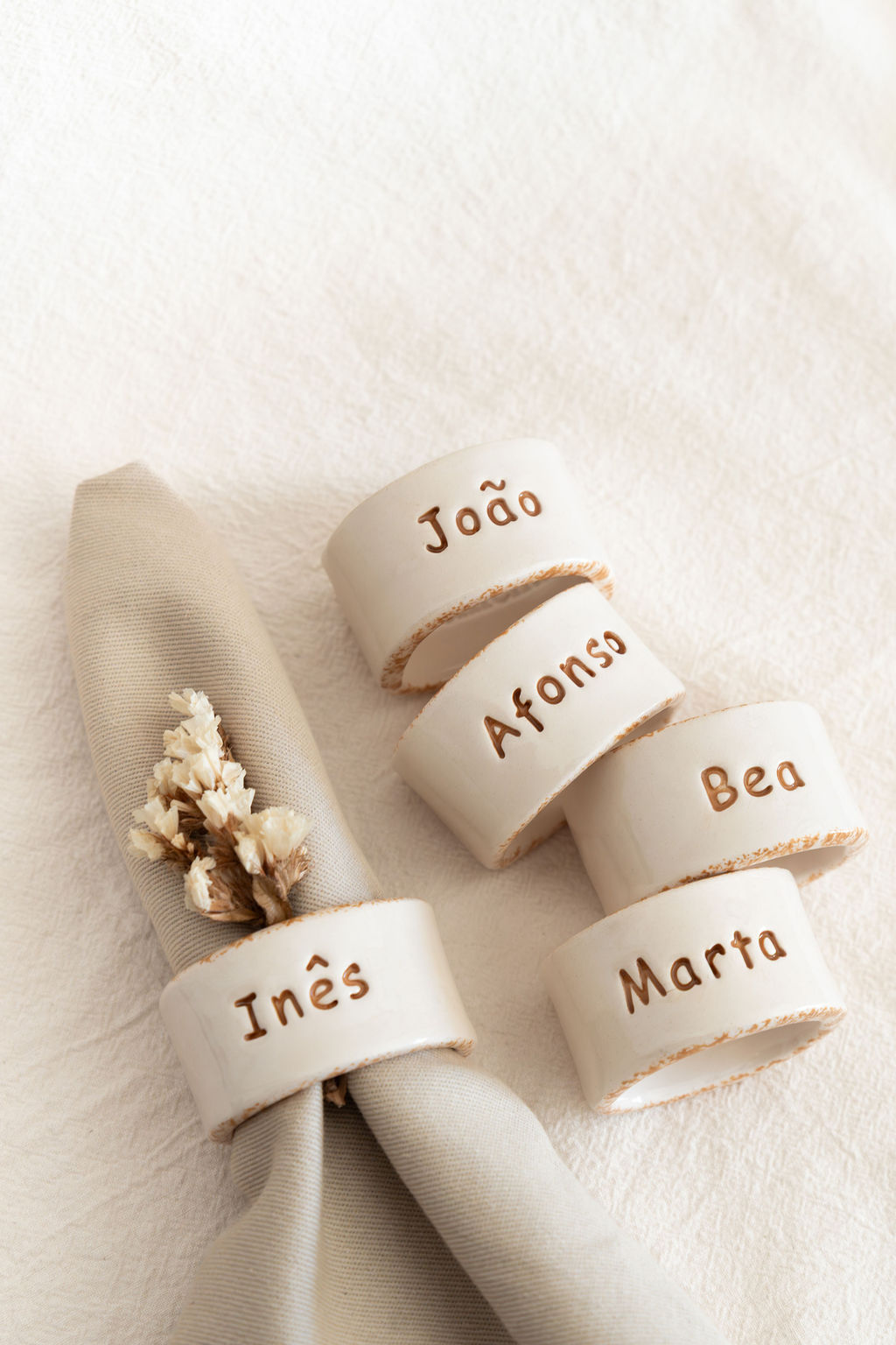 Argolas de guardanapo de cerâmica branca com nomes gravados em castanho