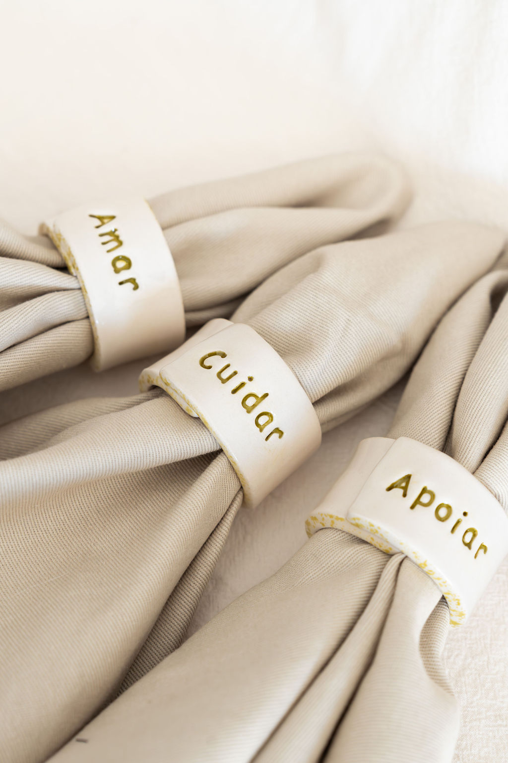 Guardanapos bege com argolas de cerâmica branca com inscrições douradas