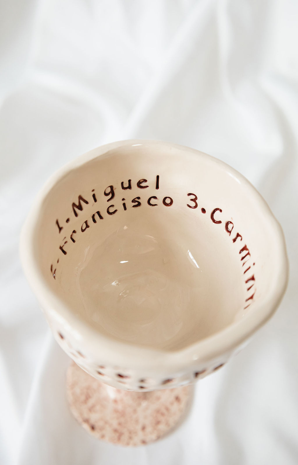 Cálice de cerâmica bege com inscrições castanhas e base texturada