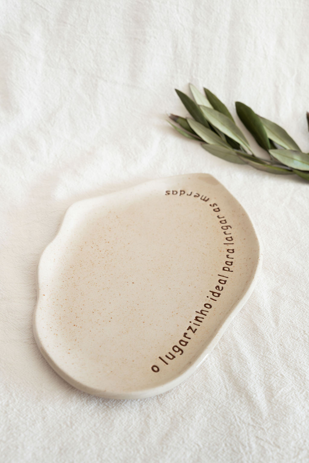 Prato em cerâmica bege com texto em português e folhas verdes ao lado