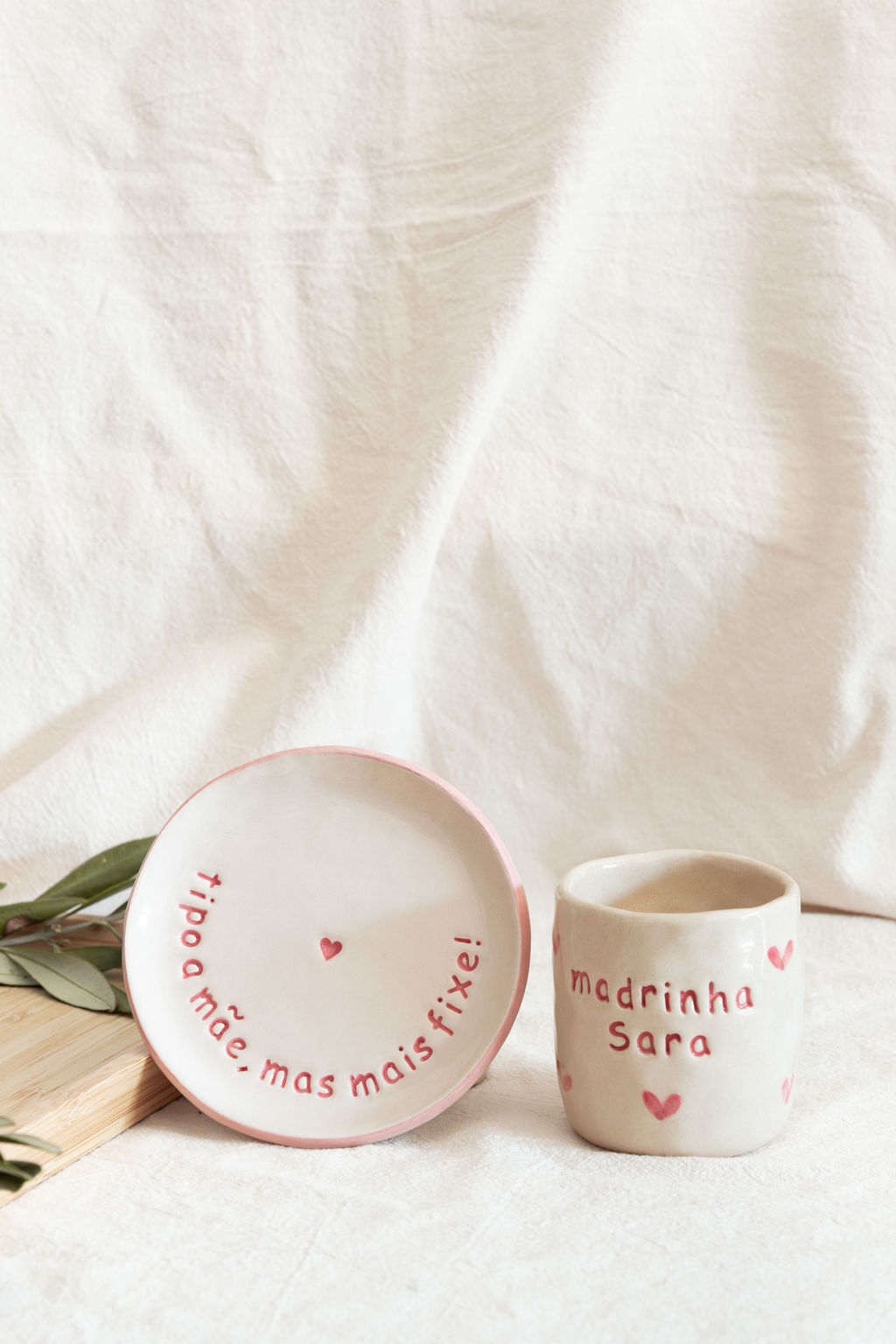 Prato e caneca de cerâmica creme com texto e corações em rosa e vermelho.