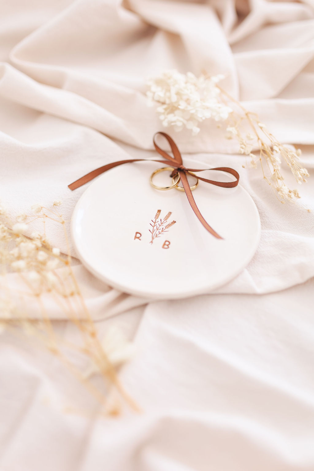 Prato cerâmico branco com decoração de ramos e fita castanha com anéis dourados