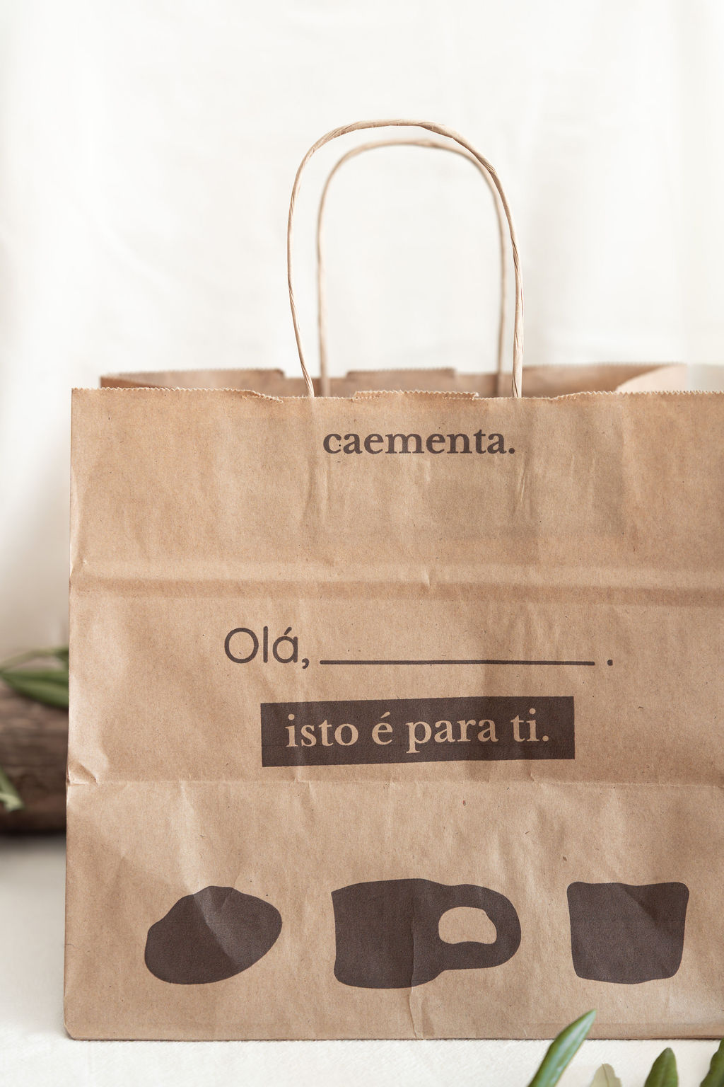 Sacola de papel castanho com texto impresso e alças torcidas