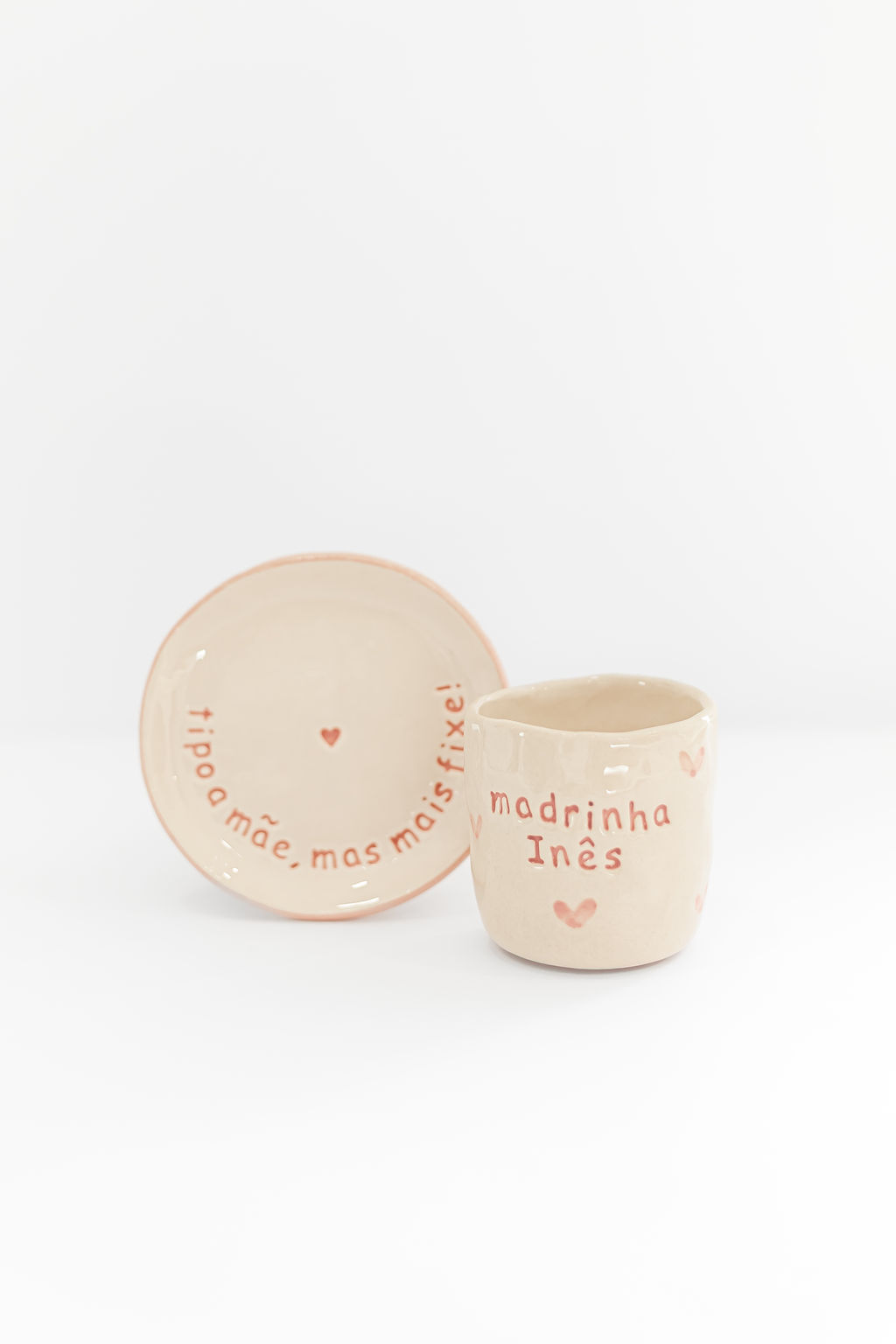 Conjunto de chávena e pires de cerâmica creme com texto vermelho e corações.