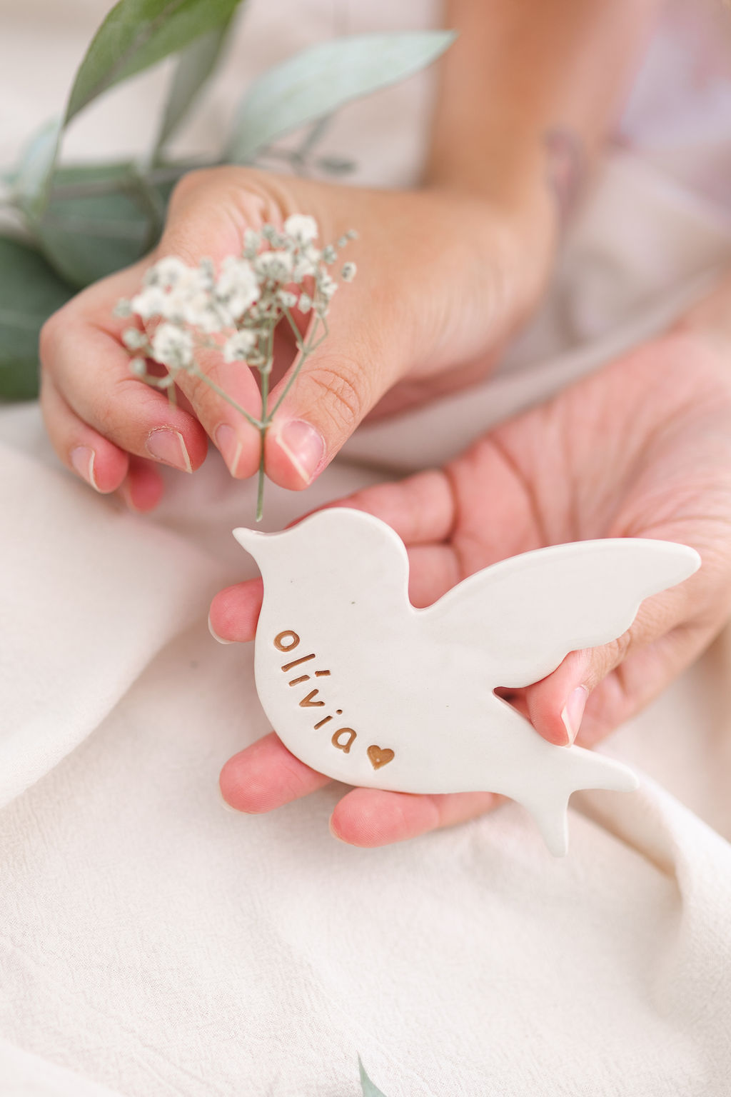 Peça decorativa de cerâmica branca em forma de pássaro com nome e coração gravados