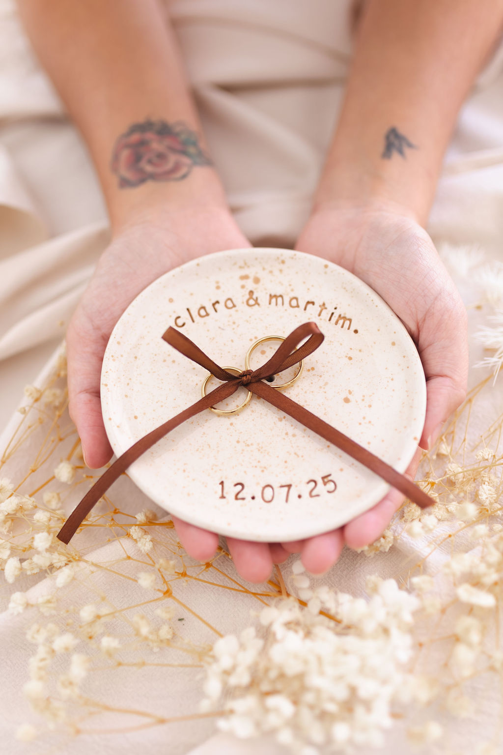 Prato de cerâmica com alianças douradas amarradas e texto personalizado