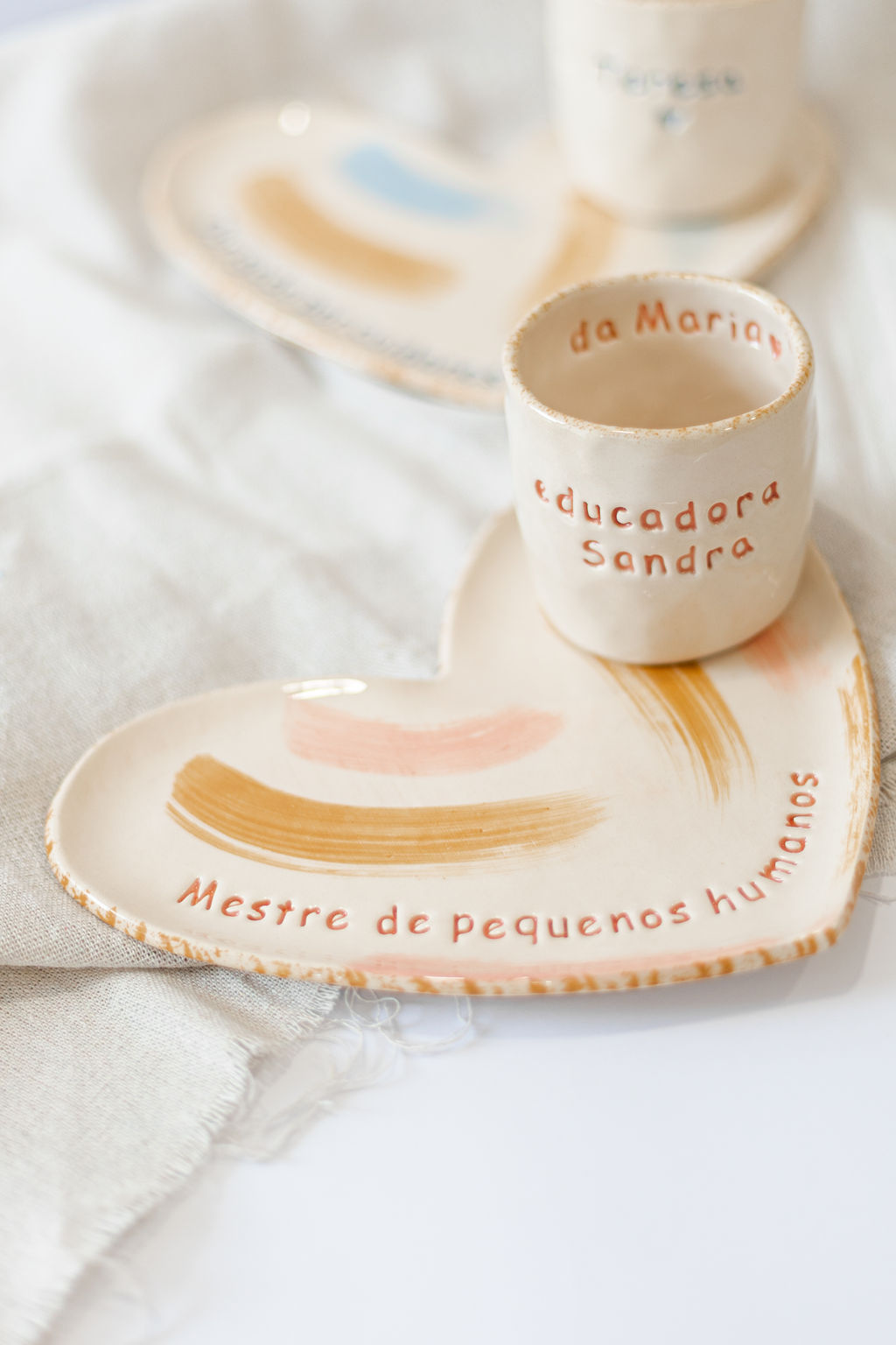 Conjunto cerâmico com base coração e copo com texto personalizado da Maria educadora Sandra.