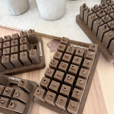 Conjuntos de carimbos em silicone castanho com letras e números, base caementa, mesa de madeira, vasos cinza claro