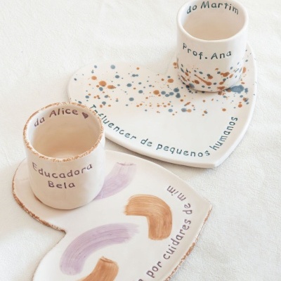 Conjunto de cerâmica branca com copos e pratos em forma de coração com decoração e texto