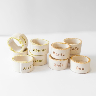 Anéis de cerâmica branca com nomes e palavras gravadas em português