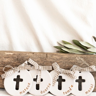 Ornamentos redondos brancos com cruz e nomes à mão colocados sobre madeira