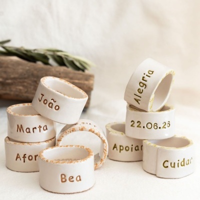 Argolas de guardanapo em cerâmica branca com textos variados e bordas castanhas e verdes