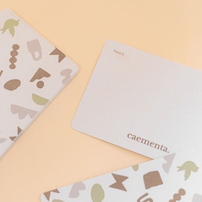 Cartões com padrões abstratos em tons terra e cartão branco com texto num fundo bege