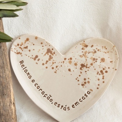 Prato de cerâmica em forma de coração com manchas e frase em português.