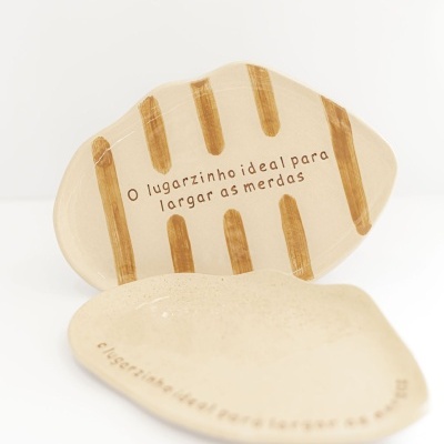 Duas peças de cerâmica bege, uma com riscas castanhas e texto, a outra lisa e com texto, sobre fundo branco.