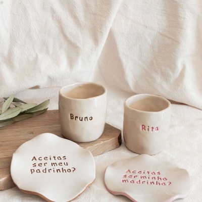 Conjunto de copos e pratos cerâmicos com inscrições para padrinhos e madrinhas.