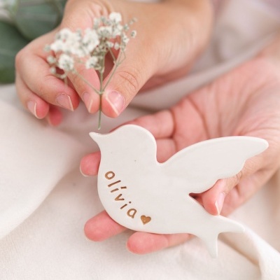 Peça decorativa de cerâmica branca em forma de pássaro com nome e coração gravados