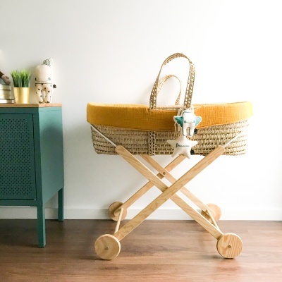 Carrinho de bebé em vime amarelo com estrutura em madeira e quatro rodas