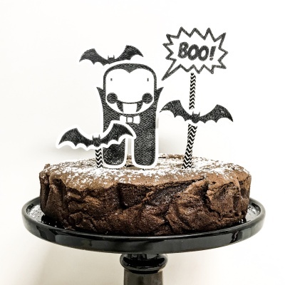 Bolo de chocolate com decorações pretas e brancas de Halloween numa base preta