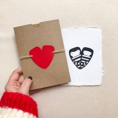 Envelope marrom com coração vermelho e folha branca com corações pretos estilizados