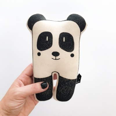 Pelúcia em forma de panda preto e branco, segurada por uma mão.