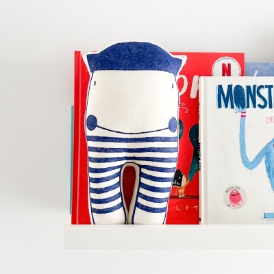 Almofada em tecido azul e branco com riscas na prateleira com livros