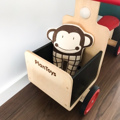 Carrinho de madeira com boneco de pelúcia de macaco