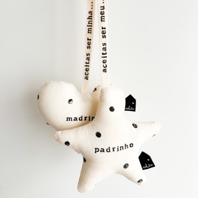 Pendurados pendentes de tecido branco com pontos pretos em forma de coração e estrela com palavras madrinha e padrinho