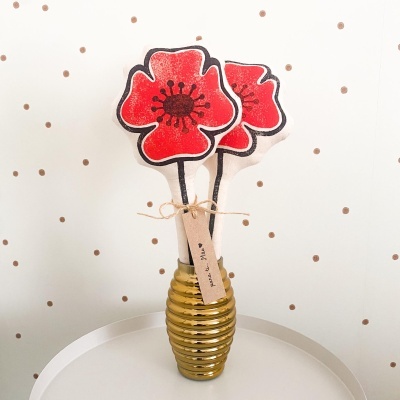 Flores decorativas vermelhas em vaso dourado sobre mesa branca