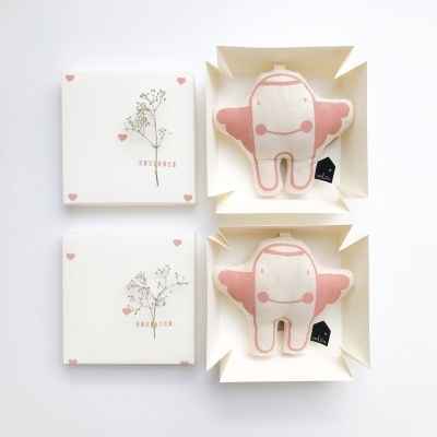 Caixas brancas com flores secas e peluches de dentes sorridentes rosa e branco