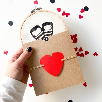 Bastidor de bordado com desenho e cartão com coração vermelho no centro