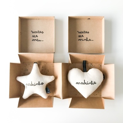 Ornamentos de tecido branco em forma de estrela e coração em caixas de cartão abertas.