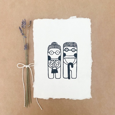 Ilustração de casal senhor e senhora em papel branco com bordas irregulares junto a ramo de flores secas