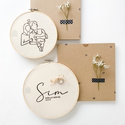 Dois bastidores bordados e cartões decorados com flores e fita preta com pontos brancos