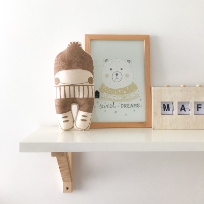 Peluche castanho e bege e quadro com ilustração de urso e texto SWEET DREAMS numa prateleira branca