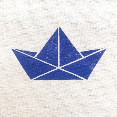 Estampa azul de barco de papel em tecido cru.