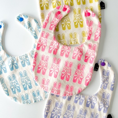 Babetes de tecido com estampado de coelhos em azul, rosa, amarelo e lilás