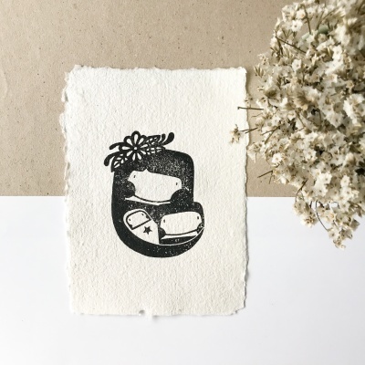 Cartão artesanal com ilustração de máquina de costura e flores, ao lado de flores secas brancas