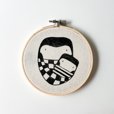 Aro bordado com estampa preta de duas formas abstratas em tecido branco