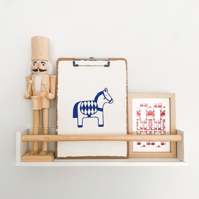Prateleira branca com soldado de madeira, quadro com cavalo azul e quadro vermelho pequeno